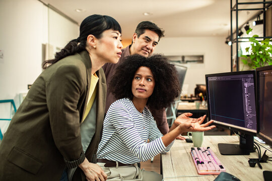Diverse coworkers collaborating on software project in modern office