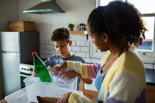 Mother and son recycling plastic bottles in home kitchen