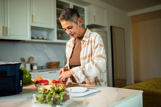Mature woman chopping vegetables in modern home kitchen