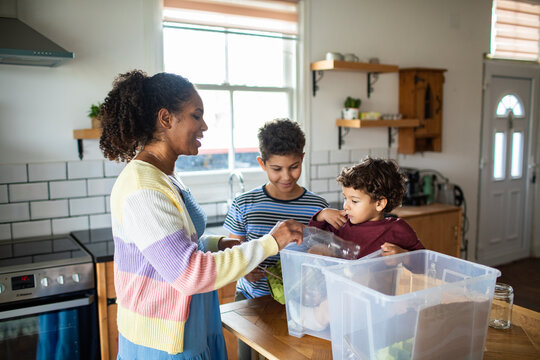 Mother and children sorting recycling in a home kitchen