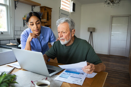 Caregiver helping senior man manage bills at home