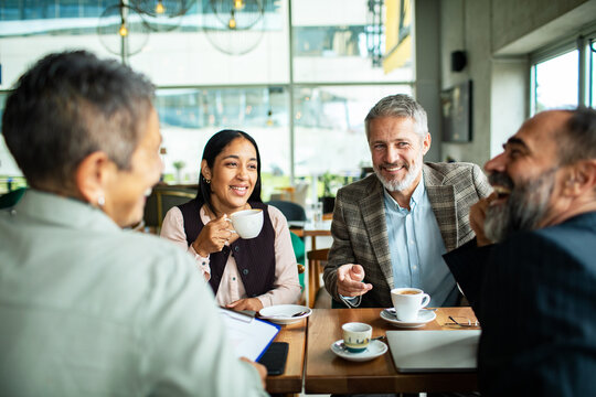 Diverse business colleagues meeting over coffee in a modern cafe