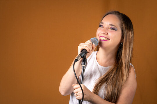 Mujer con rostro sonriente cantando con su microfono