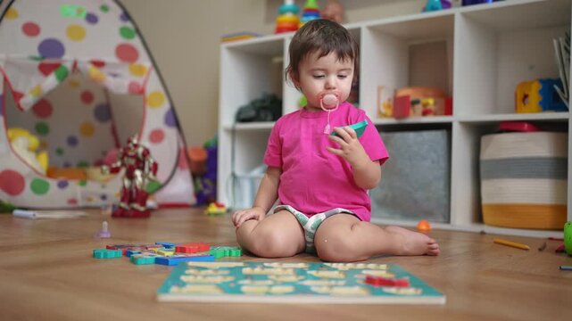 little daughter plays with toys on floor, develops fine motor skills. little daughter lifestyle learning to insert toy pictures into slots. happy family child dream concept