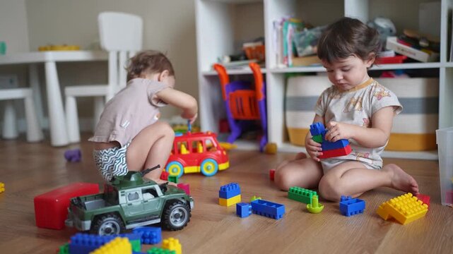 baby group children playing toys on floor in kindergarten. happy family kid concept. baby twins brother sister play toys scattered on indoors. development of fine motor dream skills concept