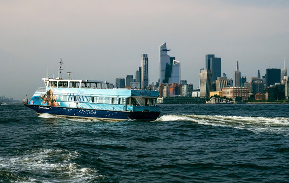 New York, NY - US - Jul 1, 2026 A NY Waterway ferry, wrapped in a "Moana" movie advertisement, glides across the Hudson River. Behind it, the iconic Hudson Yards and Midtown Manhattan skyline tower.