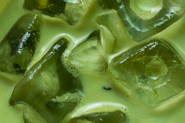 Macro Close-Up of Iced Japanese Matcha Latte with Crystal Clear Ice Cubes and Creamy Green Tea Texture © Latthaphon