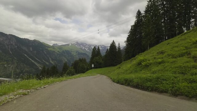 A professional road cyclist conquering a steep asphalt climb on a winding mountain road to the Fellhorn peak during an intense endurance training and road bike trip in Oberstdorf Bavarian Alps