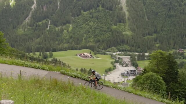Active lifestyle and sport vacation concept featuring a determined road cyclist on a gravel bike pushing hard uphill on a scenic pass road to Fellhorn mountain in Oberstdorf Germany