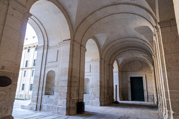 Fototapeta premium San Lorenzo de El Escorial, Spain. Interior view of the sixteenth century granite stone vaulted narthex and entry portal of the basilica opening towards the Patio de los Reyes courtyard
