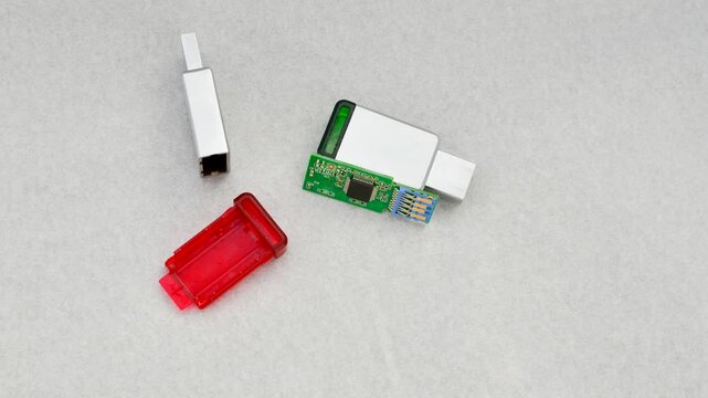 Close-up of a disassembled USB flash drive on a white background, revealing its internal complexity. Close-up of an open USB flash drive, exposing circuits and connections, on a white surface.