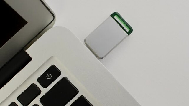 Detail of a USB drive next to a laptop, representing portable technology and fast data transfer.
