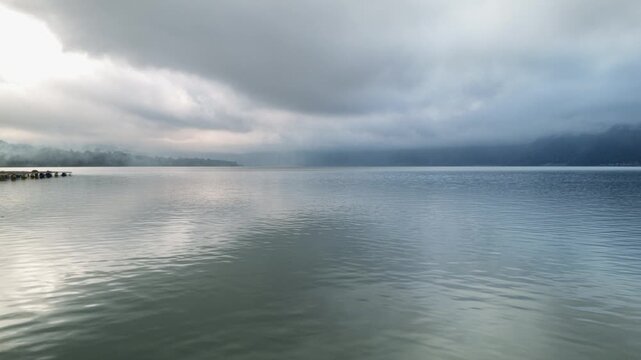 Overcast and Moody Lake Landscape with Thick Clouds and Mist Over Water