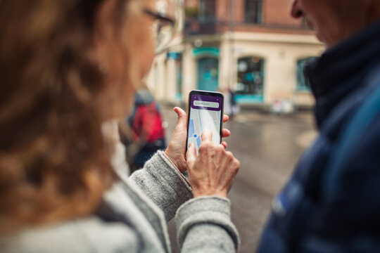 Mature couple using smartphone navigation in city street