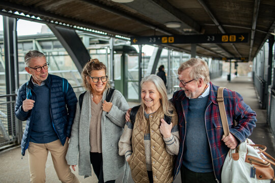 Happy senior friends walking at train station platform