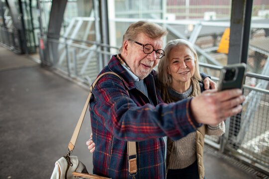 Senior couple taking selfie at train station