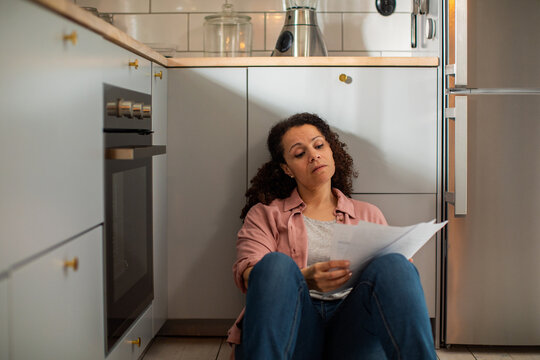 Concerned woman reading household bills in kitchen