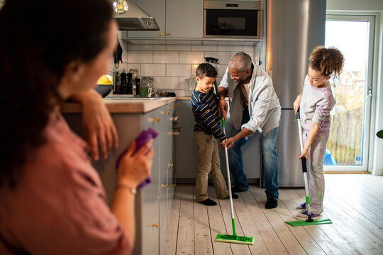Parents and children cleaning together in modern kitchen