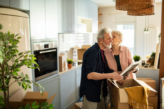 Senior couple unpacking boxes and kissing in new kitchen