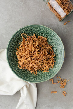 overhead view of thin nigerian chin chin in a green bowl on a grey countertop, top view of thin fried chin-chin in a green plate, Fried chin-chin snack on a platter, Nigerian party food