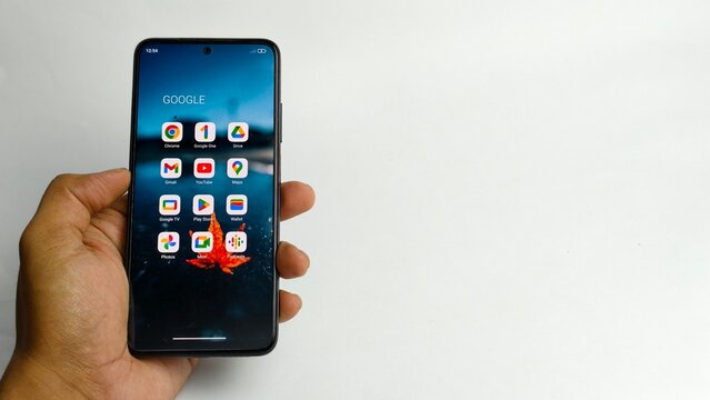 Ipoh,Malaysia - 04 July 2026: A hand holds a smartphone displaying Google application icons on its screen, positioned against a plain white background.