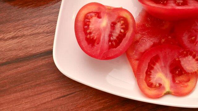 Fresh Red Tomato: Succulent slices on a white plate, ready to inspire your culinary creations. Close-up of sliced red tomatoes, an appetizing sight to awaken the taste buds.