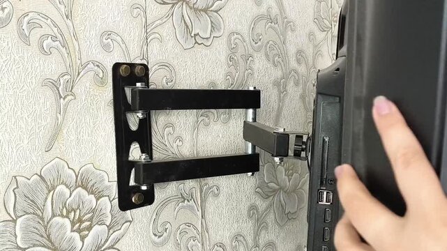 Person checking stability of installed TV wall mount, installation safety, home improvement and mounting concept.