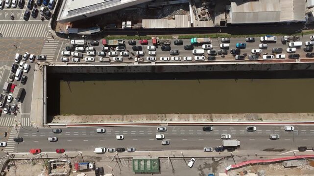 Urban canal and busy traffic intersection along Tamanduate&iacute; river in S&atilde;o Paulo. Travelling overhead camera movement