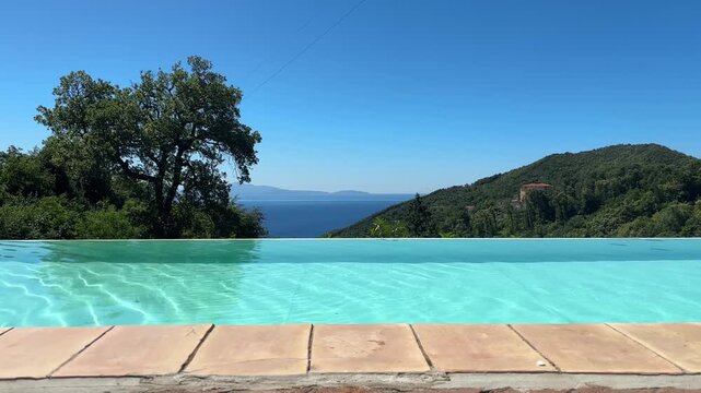 Infinity pool blending into distant sea and mountain view, perfect concept for villa vacation and mediterranean getaway in Italy
