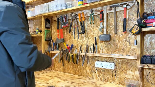 Person in gray jacket organizes various tools on a wooden workbench, showcasing a progression of actions in a well-equipped workshop environment