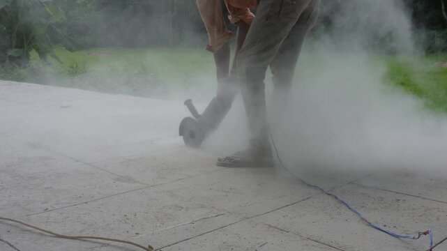 Worker cutting concrete with powerful dust cloud