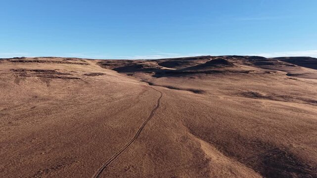 Aerial drone footage flies over a two-track road through the barren, rolling hills of the Smoke Creek Desert near the Nevada state line, Lassen County, California.