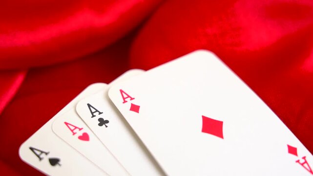 Close up view of four aces playing cards fanned out on red silk fabric poker game gambling casino