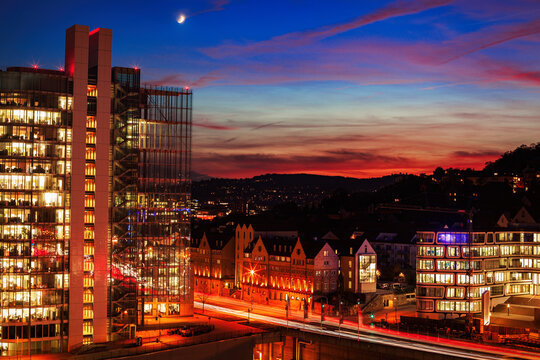 City skyline at sunset with illuminated buildings and moon