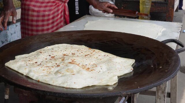 Person cooking flatbread on hot tawa with care