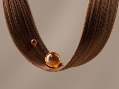 A strand of smooth brown hair curves through the frame, holding two glistening amber oil droplets.