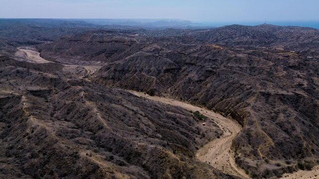 Aerial View of Winding Dirt Road Through Dry Coastal Hills in Ecuador, Rugged Ravines, Sparse Vegetation and Remote Arid Landscape Background
