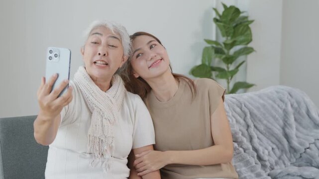 Grandmother and granddaughter making a video call together at home, representing family communication, remote connection, senior technology, digital lifestyle and social bonding.