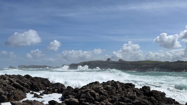 Elevated panoramic view of the Atlantic storm along the Cantabrian coast, revealing the full scale of powerful rolling ocean swells and massive wave explosions along the rocky shoreline.