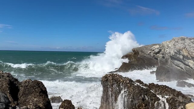 Powerful Atlantic waves crash against the rocky coastline of Costa Quebrada beneath a clear blue sky. Static coastal footage with turquoise water, white sea spray, natural ocean sound and an immersive