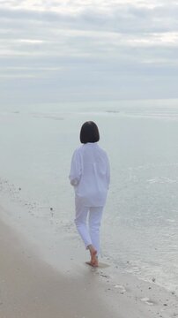 Woman walking barefoot along a peaceful beach