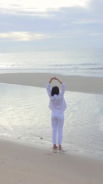 Woman stretching on a peaceful beach at sunrise, embracing relaxation, mindfulness, wellness, and the calming beauty of the ocean.