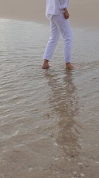 Barefoot walking along a peaceful beach shoreline with gentle ocean waves,