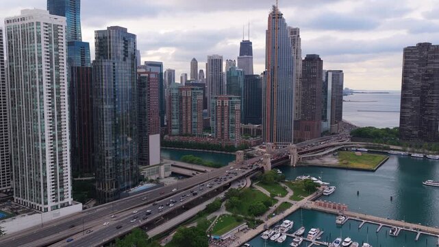 Chicago skyline with John Hancock Center overlooking Lake Michigan, cars driving on Lake Shore Drive bridge over Chicago River with boats moored in DuSable harbor
