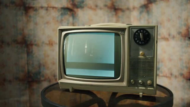 A vintage television flickers with nostalgic black and white static, surrounded by warm lighting and classic decor. This setup evokes memories of past technologies and cozy evenings