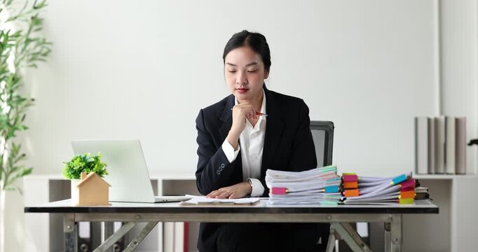 Businesswoman concentrating on a large stack of documents, managing heavy workload