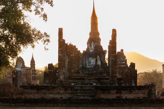 Ancient Buddha statue at Sukhothai Historical Park during sunset, Thailand.