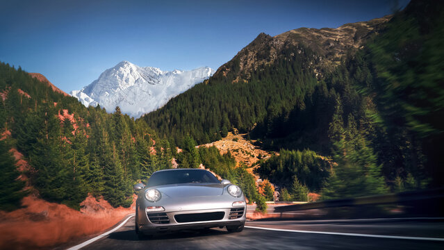 Silver sports car driving mountain road with snowy peaks