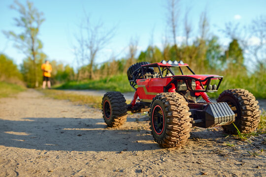 Remote control off-road car on a dirt path, child playing outdoors, summer hobby, adventure and leisure concept
