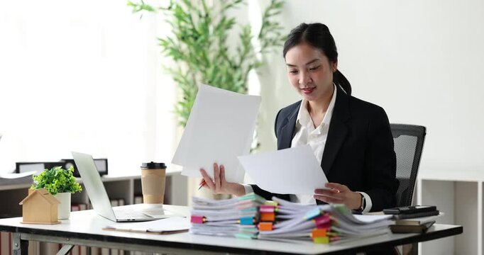 Businesswoman concentrating on a large stack of documents, managing heavy workload